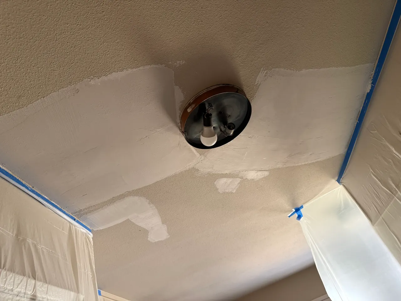 Ceiling crack repair in Richardson, TX, with fresh joint compound and the room taped off