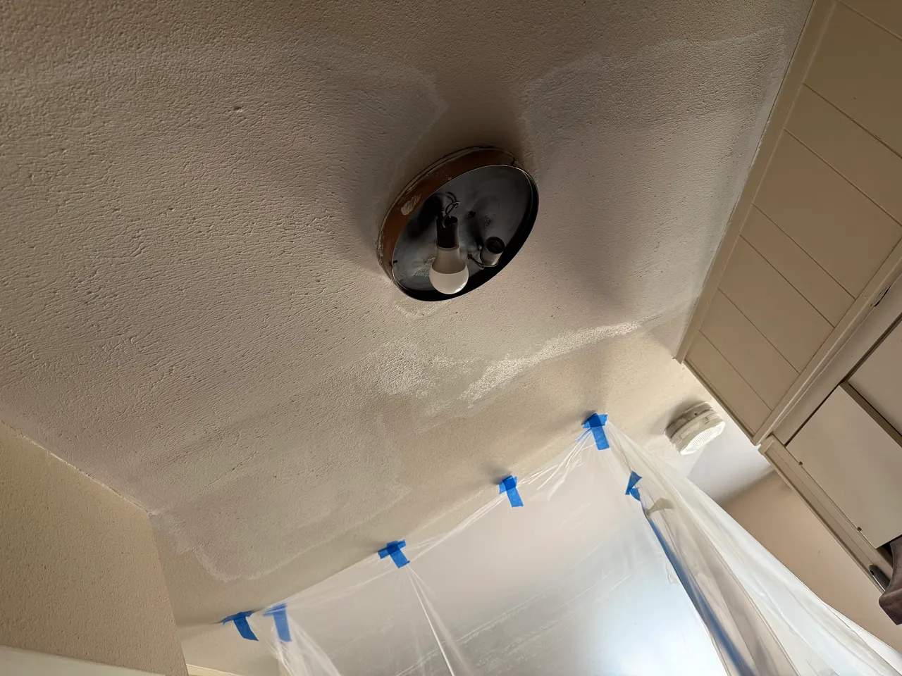 Ceiling drywall repair in Richardson, TX, with the room sealed in plastic to contain dust