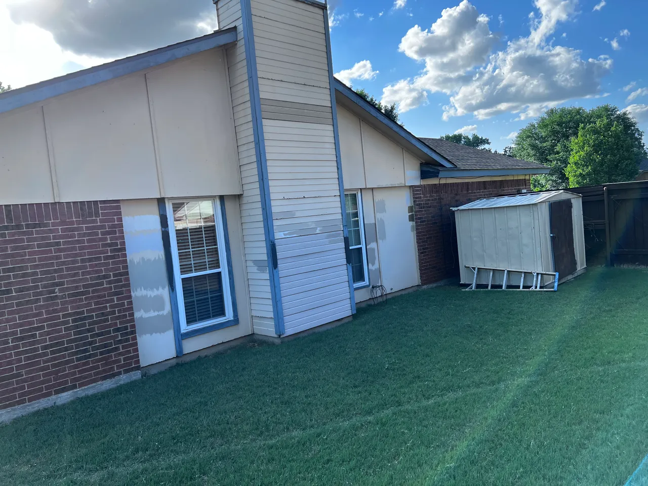 Worn chimney and gable siding with patched paint before replacement in Garland, TX