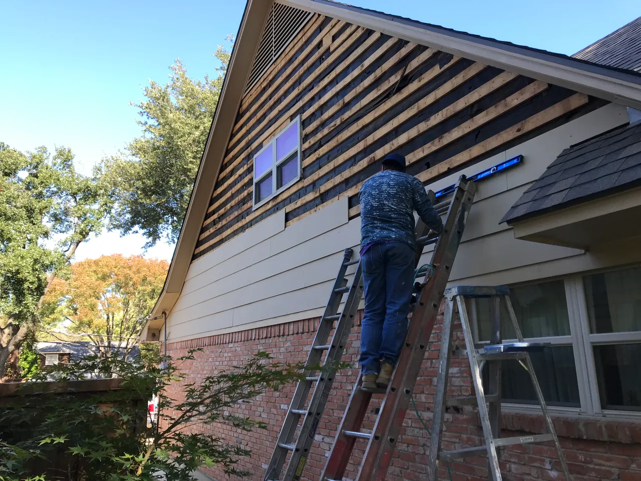 New lap siding installation in progress on a two-story gable in Dallas, TX